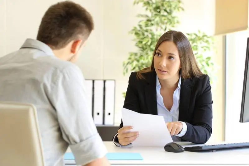 A woman is interviewing a man in an office setting.