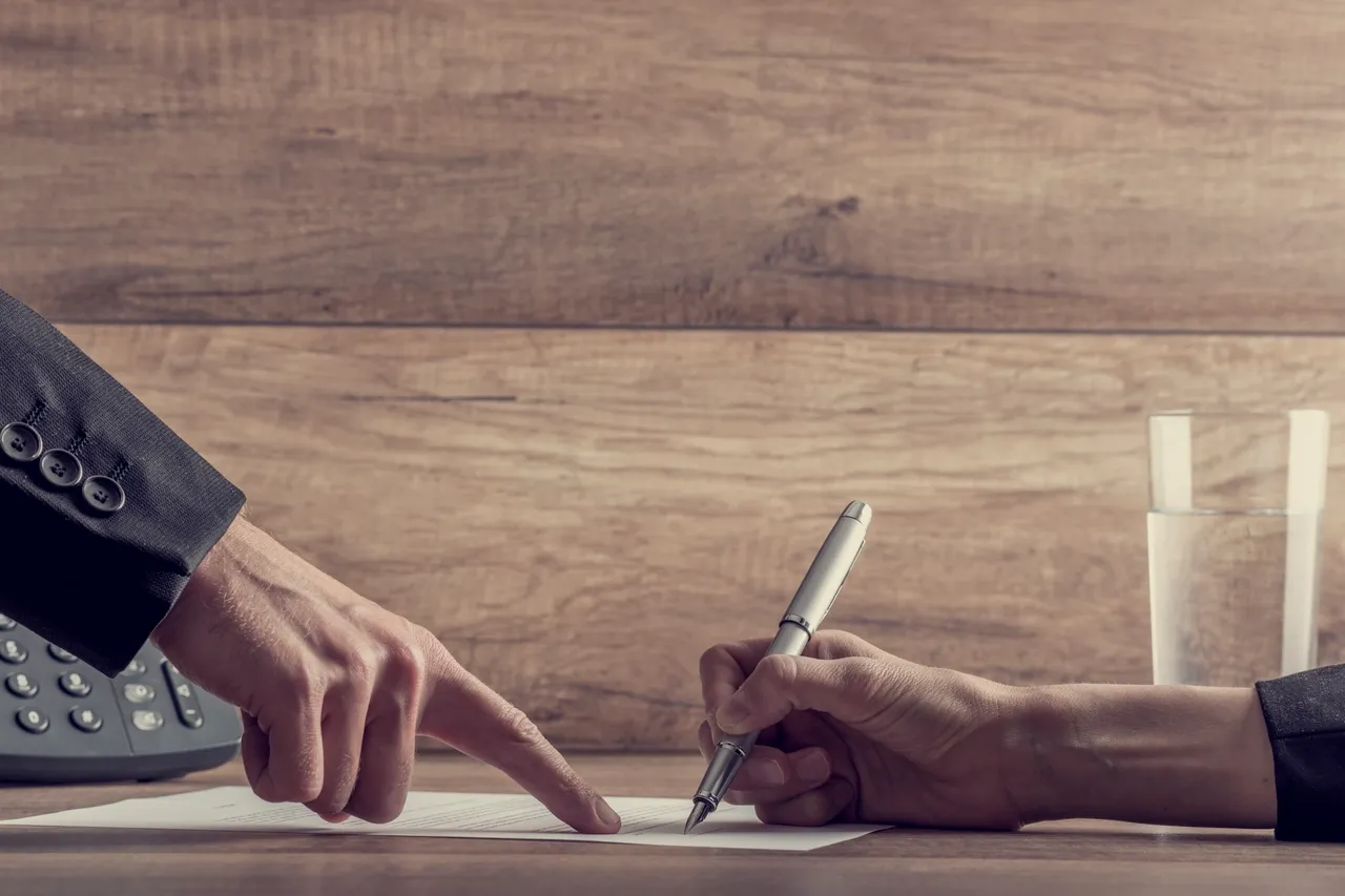 Two people are writing on a piece of paper.